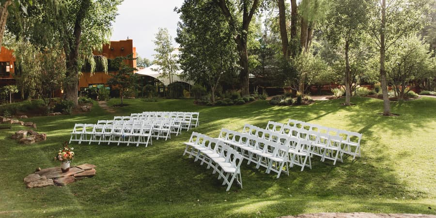 Rows of ceremony chairs set on the tree-shaded lawn at El Monte Sagrado in Taos