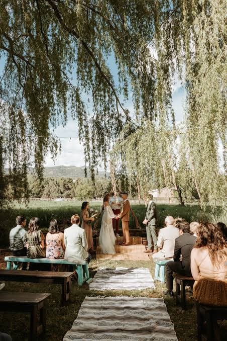 Outdoor wedding ceremony under willow trees with mountain views at Many Feathers Ranch near Taos